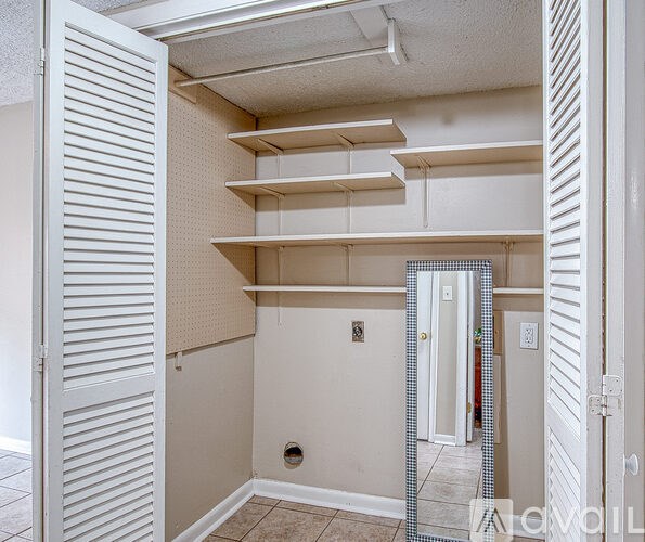 A white closet with shelves and a mirror.