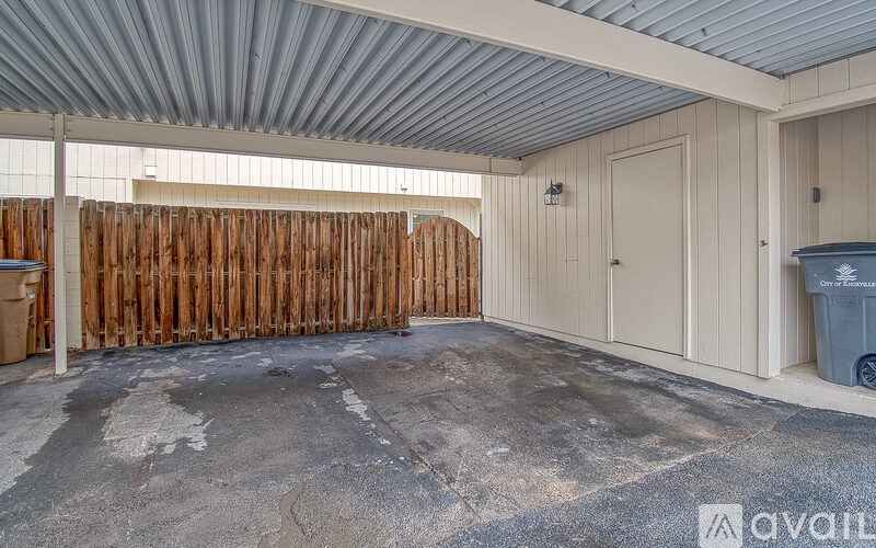 A room with a wooden fence and a grey trash bin.