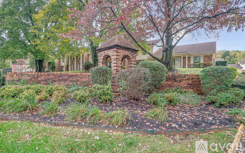 A garden with a brick wall and a gazebo.