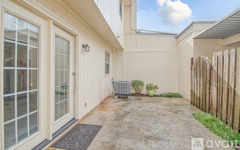 A patio area with a grey rug, a grey planter, and a wooden fence.