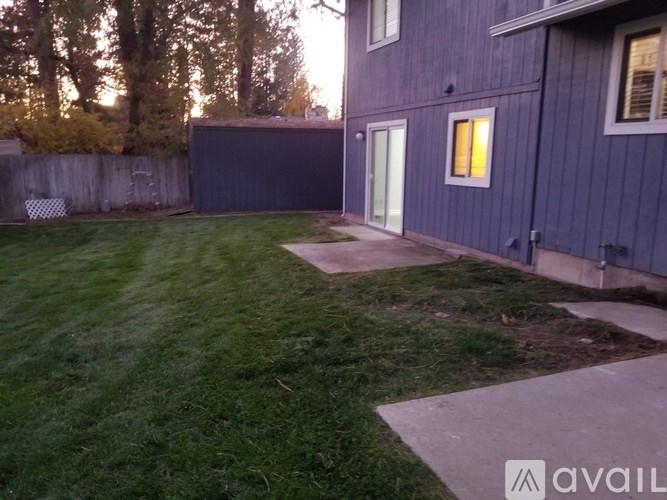 A backyard with a concrete walkway and a blue house.