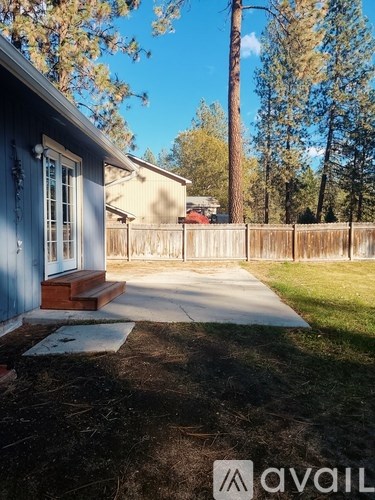 A blue house with a white fence and a tree in the background.