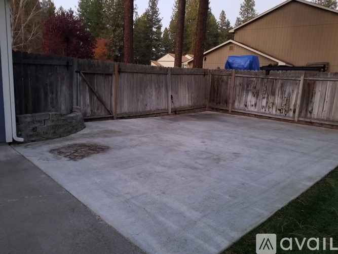 A backyard with a concrete patio and a wooden fence.