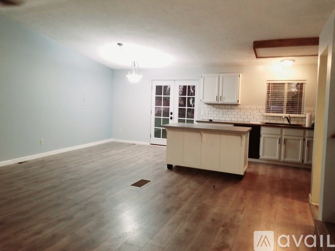 A kitchen area with a white cabinetry and a wooden floor.