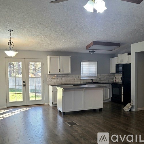 A kitchen with white cabinets and a black refrigerator.