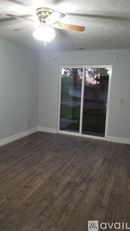 A room with a sliding glass door and wooden flooring.