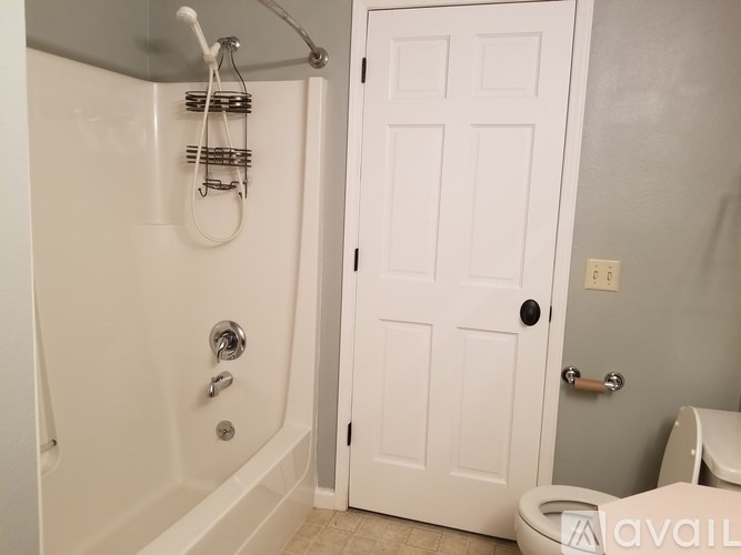 A white door is in a bathroom with a toilet in front of it.