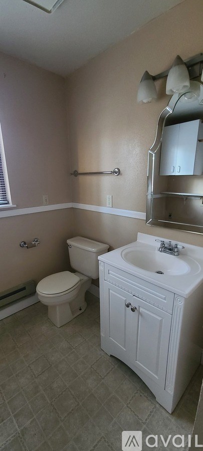 A bathroom with a toilet, sink, and a mirror.