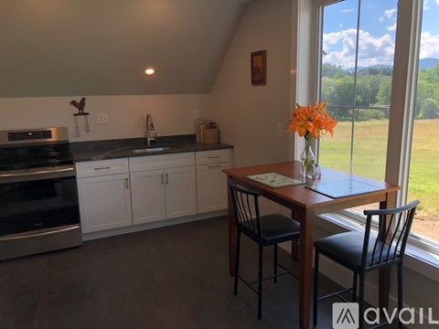 A kitchen with a table and chairs by a window.
