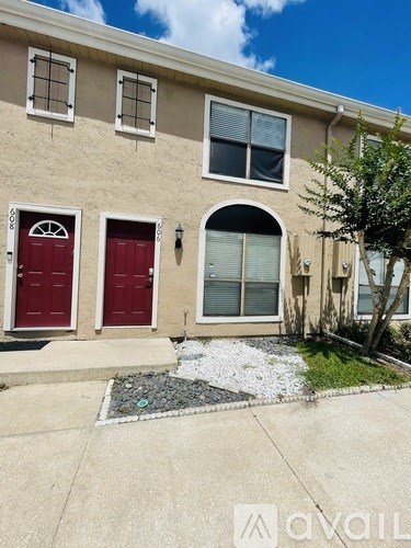 A beige house with red doors and windows.