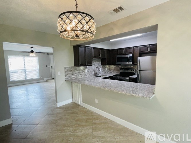 A kitchen with a granite countertop and a chandelier hanging from the ceiling.