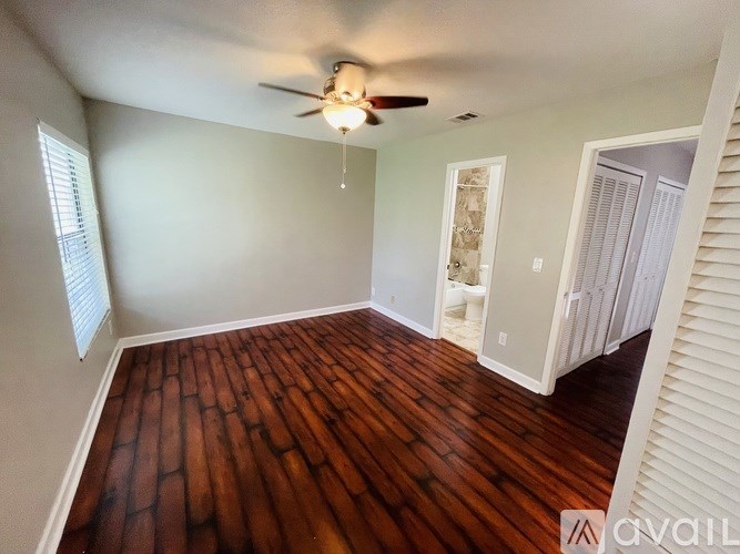 A room with a ceiling fan and wooden flooring.