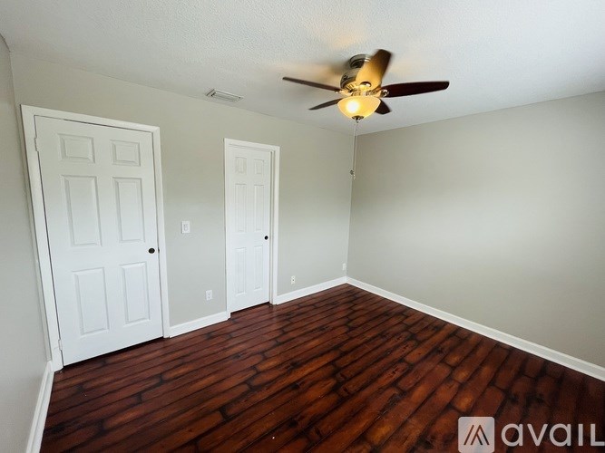 A room with a ceiling fan and wooden flooring.