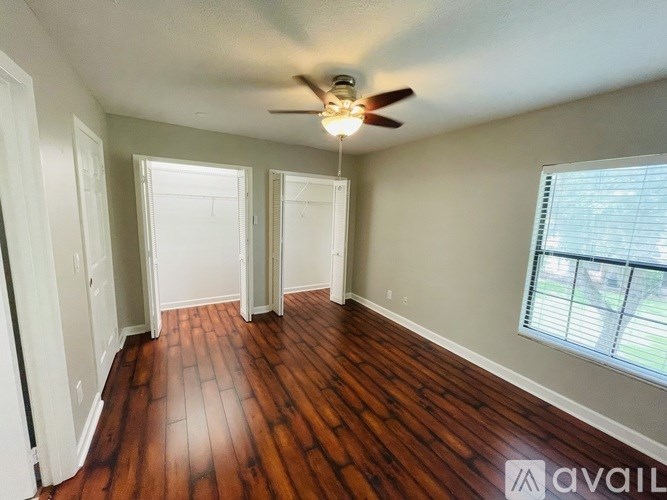A room with a ceiling fan and wooden flooring.