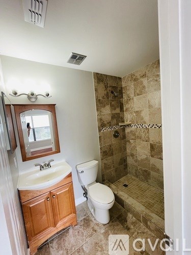 A bathroom with a toilet, sink, and tiled shower.