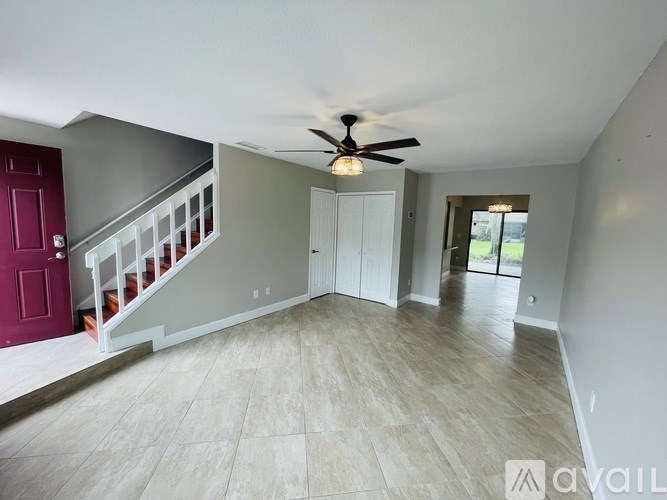 A spacious room with a staircase and a ceiling fan.