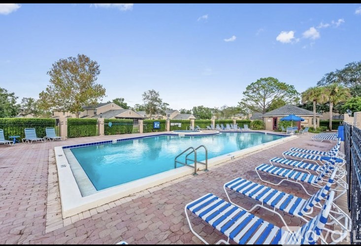 A pool surrounded by blue and white striped lounge chairs.