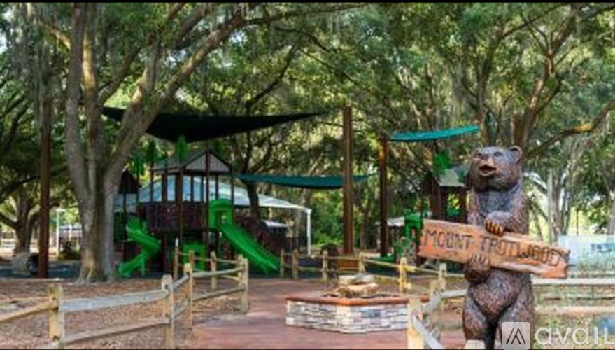 A playground with a bear statue holding a sign that says "McClintock Trail".
