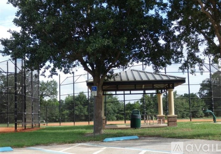 A gazebo is located in a park with a baseball field in the background.