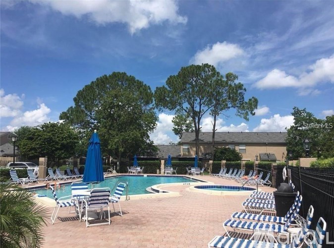 A pool area with chairs and umbrellas on a sunny day.