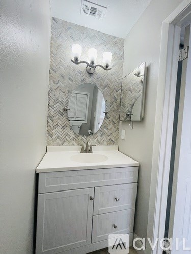A bathroom with a white sink and a mirror above it.