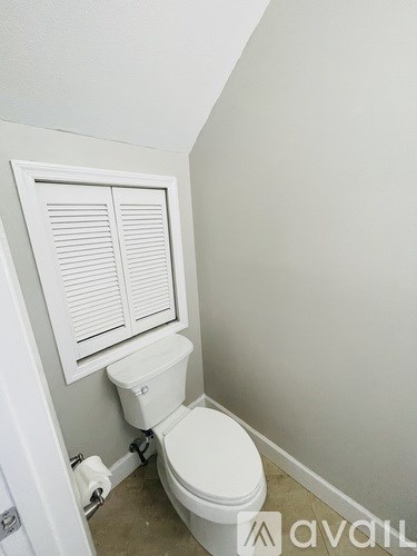 A white toilet with a white towel hanging on the wall.