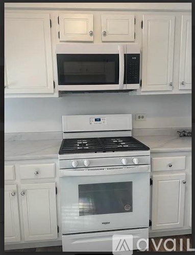 A white kitchen with a stove top oven and microwave above it.