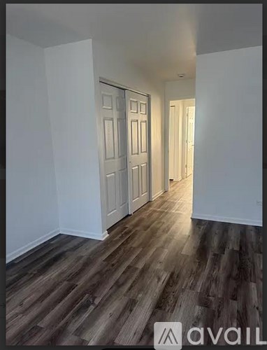 A hallway with wooden floors and white walls.