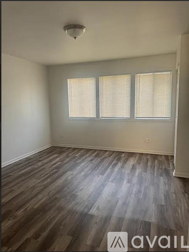 A room with wooden flooring and two windows.