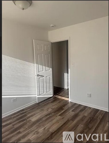 A room with a white door and wooden flooring.