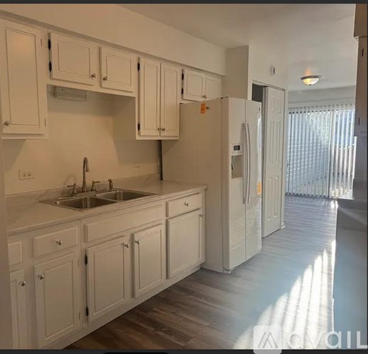 A kitchen with white cabinets and a white fridge.