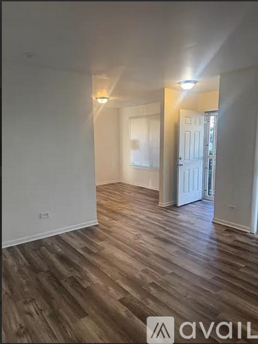 A room with wooden flooring and white walls.