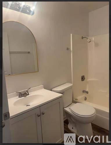 A bathroom with a toilet, sink, and mirror.