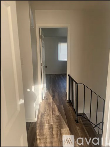 A hallway with a wooden floor and a metal railing.