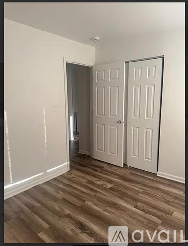 A room with a white door and a wooden floor.