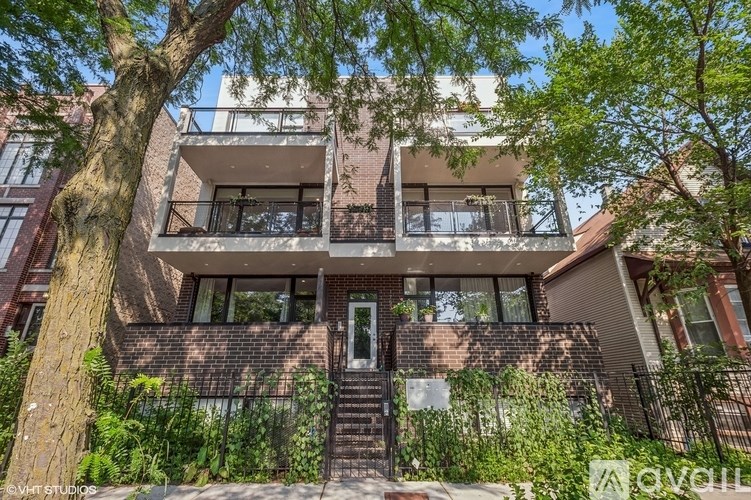 A tree in front of a brick building with a black gate.