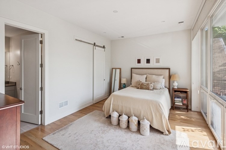 A bedroom with a bed, nightstand, and a window with a view of a city.