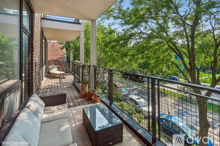 A balcony with a table and chairs overlooks a street.