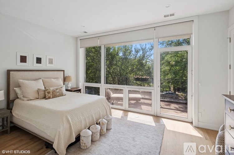 A bedroom with a large bed and a view of trees through the sliding glass doors.
