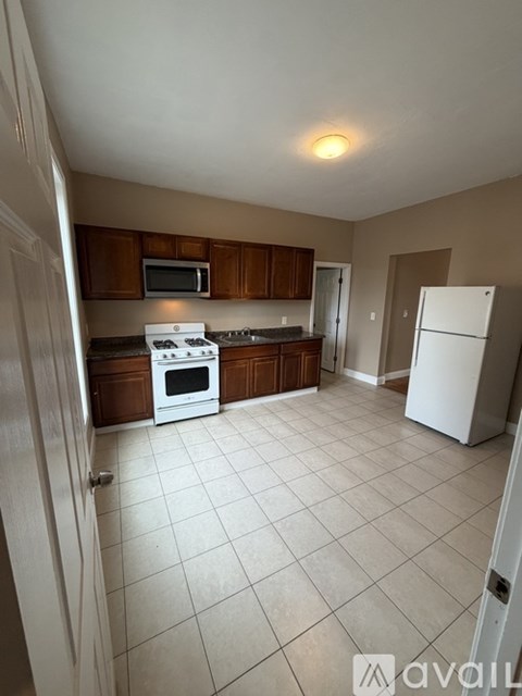 A kitchen with white appliances and brown cabinets.