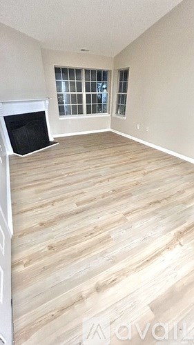 A room with wooden flooring and a fireplace.