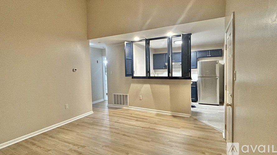 A spacious room with wooden flooring and a wall-mounted television.
