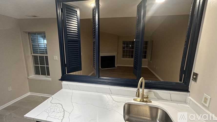A bathroom with a sink, mirror, and a window.
