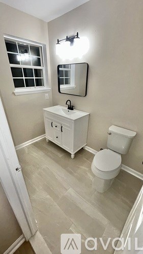 A bathroom with a toilet, sink, and mirror.