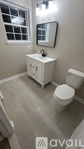 A bathroom with a toilet, sink, and mirror.