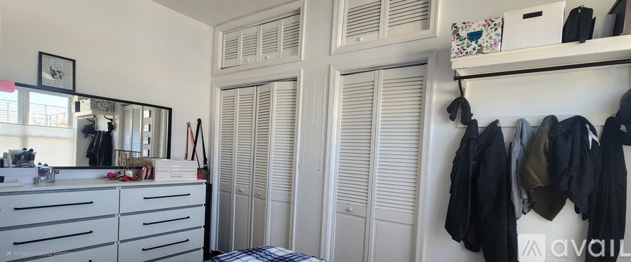 Closet with clothes hanging and a mirror above a dresser.