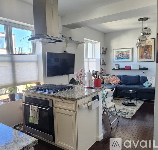 A modern kitchen with a large island and a flat screen TV mounted above it.