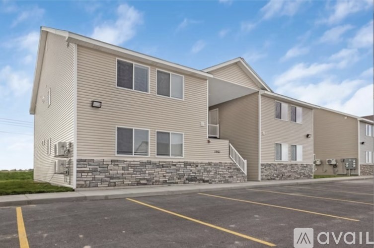 A building with a stone wall and a parking lot in front.