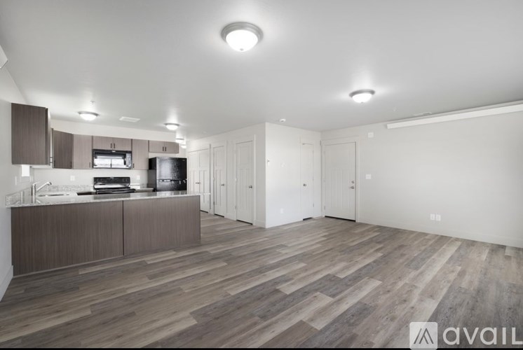 A modern kitchen with wooden flooring and white walls.