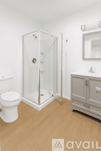 A white toilet sits next to a walk-in shower in a bathroom.